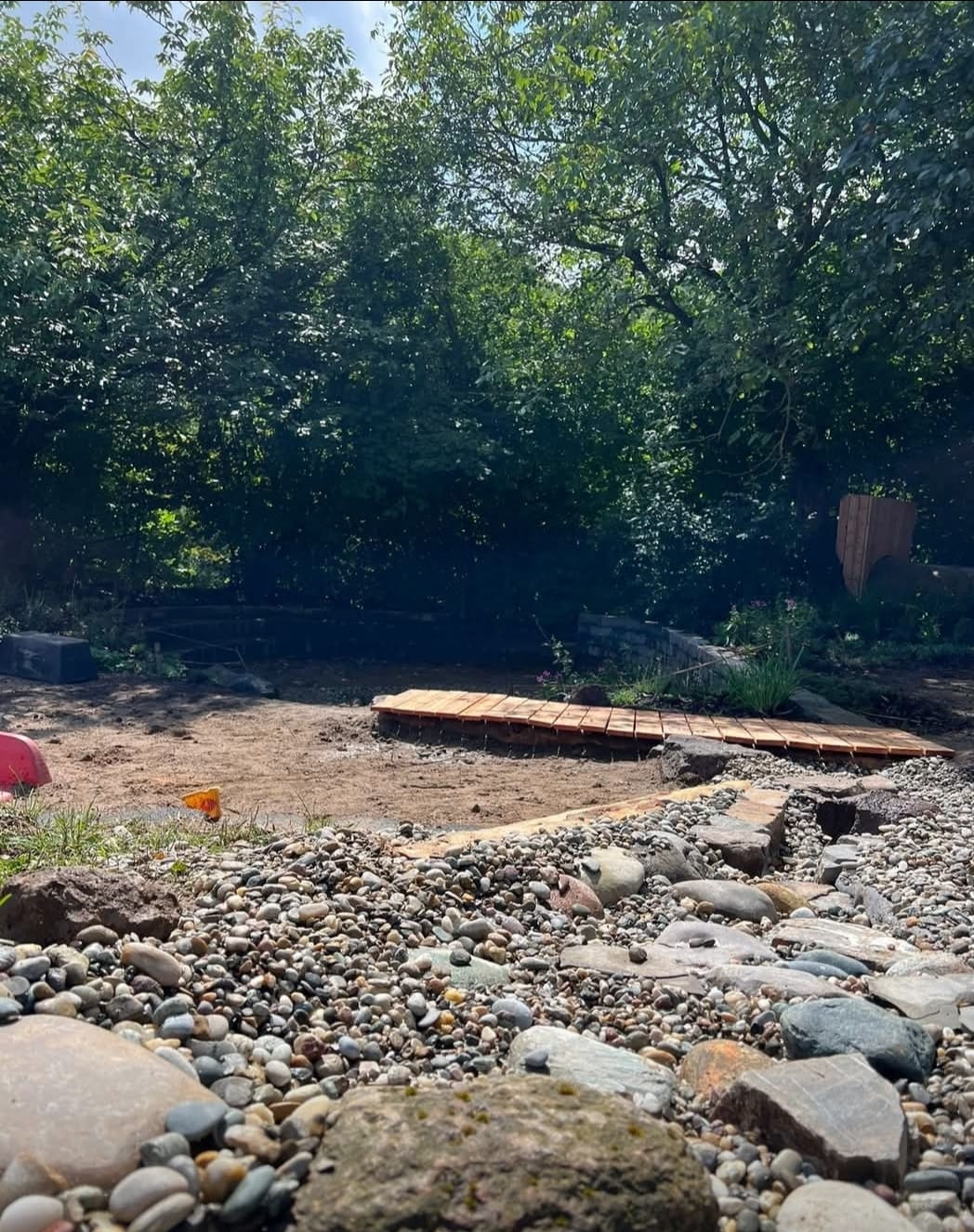 Naturteich mit Kiesufer und Holzsteg im Bau
